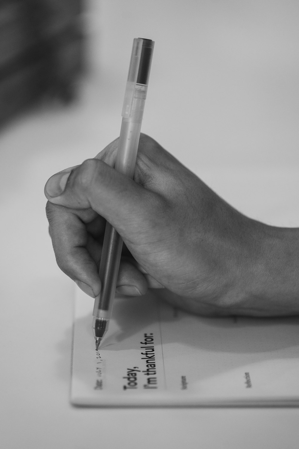 a person's hand holding a pen and writing on a piece of paper