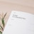 A close-up view of a journal page with headings such as 'Date' and 'Today, I'm thankful for', alongside sections titled 'Scripture' and 'Reflection'. There is also a small sprig of leaves placed on a light wooden surface.