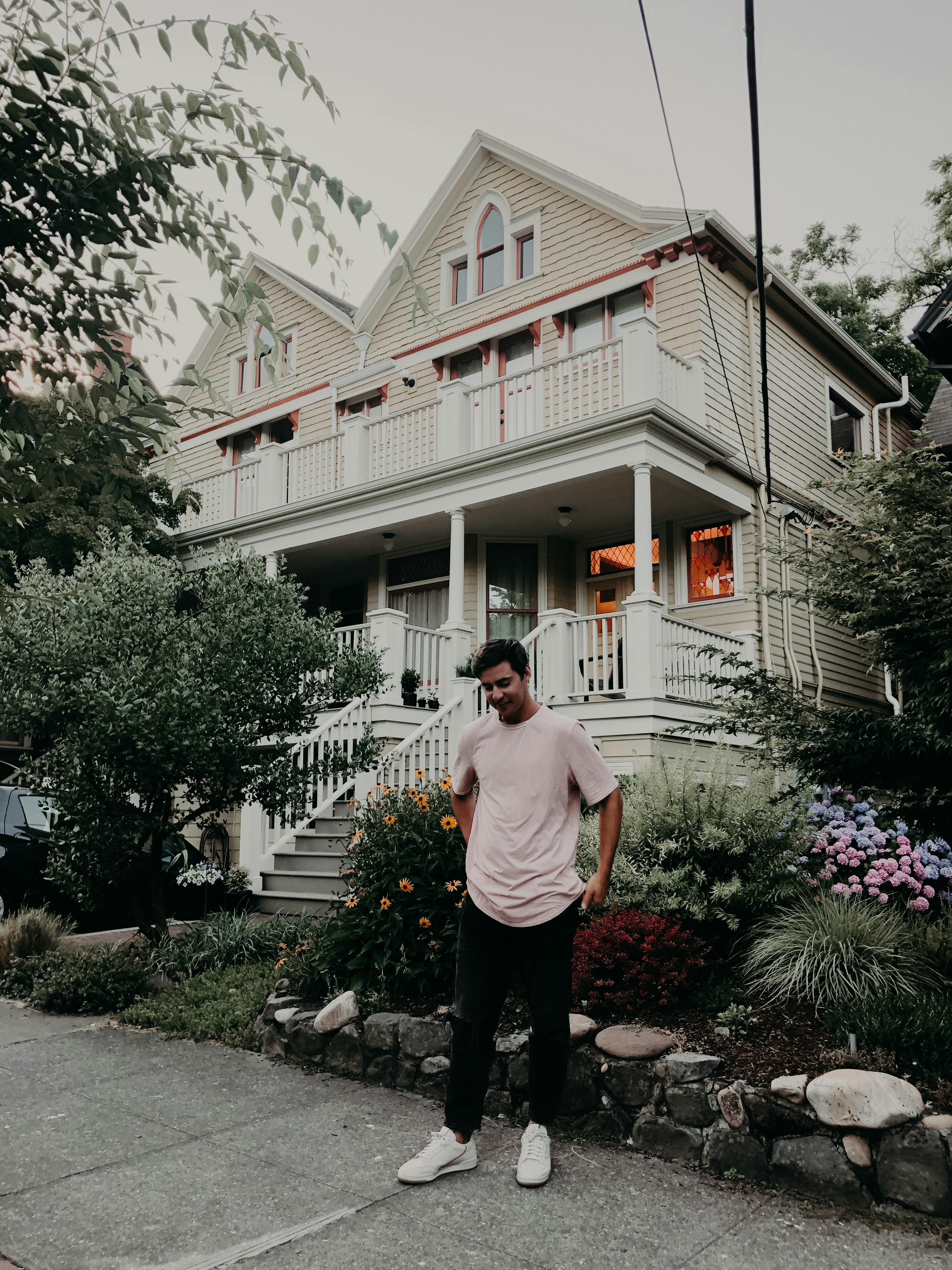 Homme portant un t-shirt blanc à col rond debout près d’une maison ...
