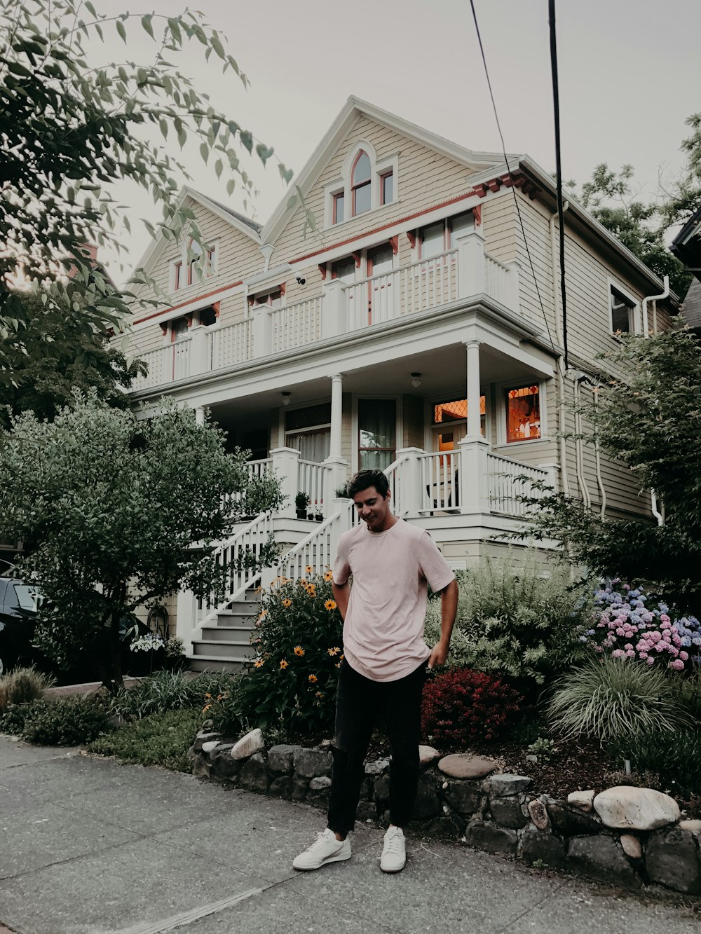 man wearing white crew-neck T-shirt standing near white 3-storey house