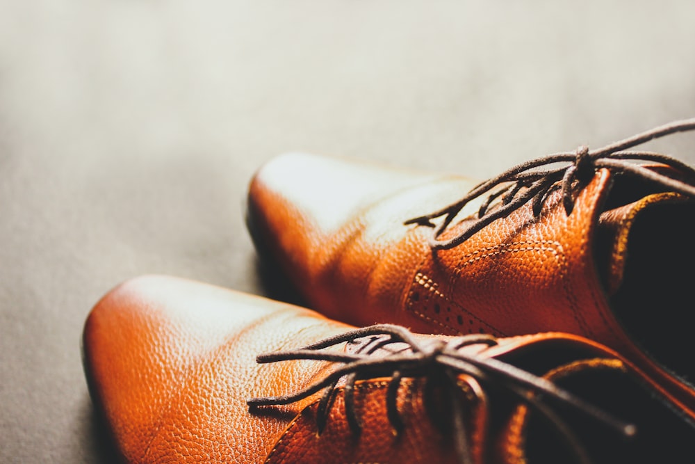 a pair of brown shoes sitting on top of a floor