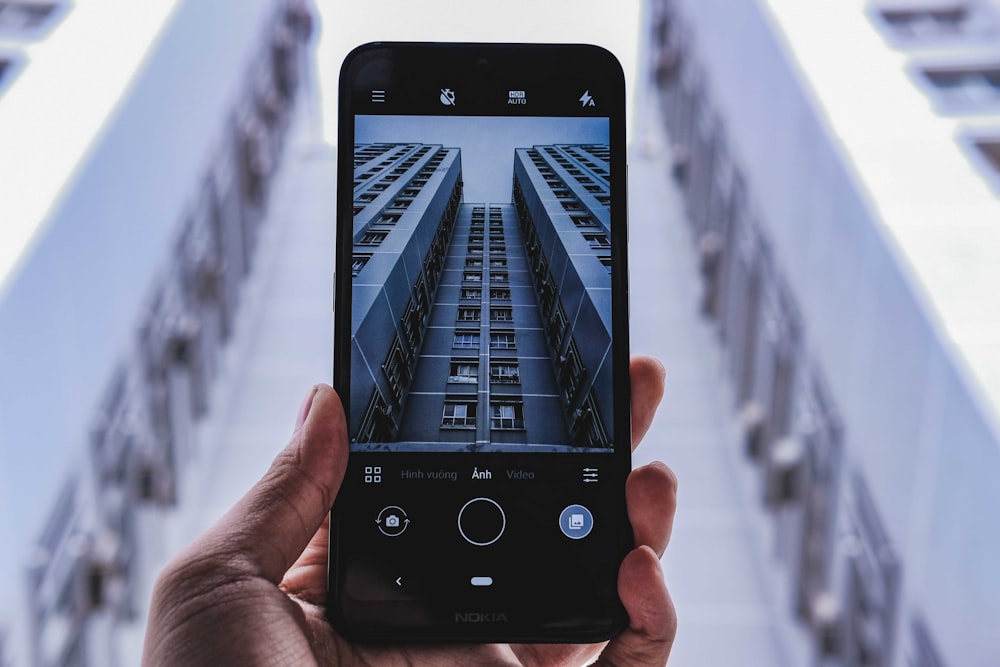 person taking photo of high-rise building