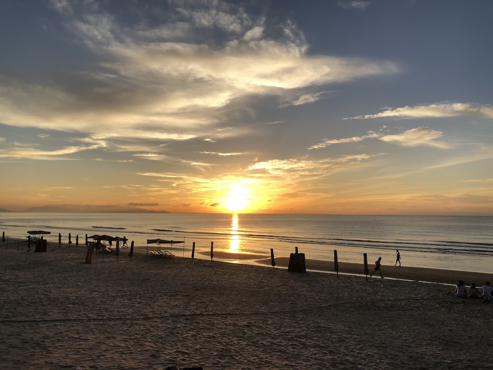 the sun is setting over the ocean on the beach