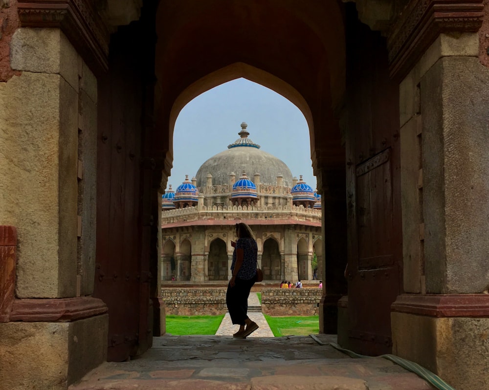 a person standing under an archway with a building in the background