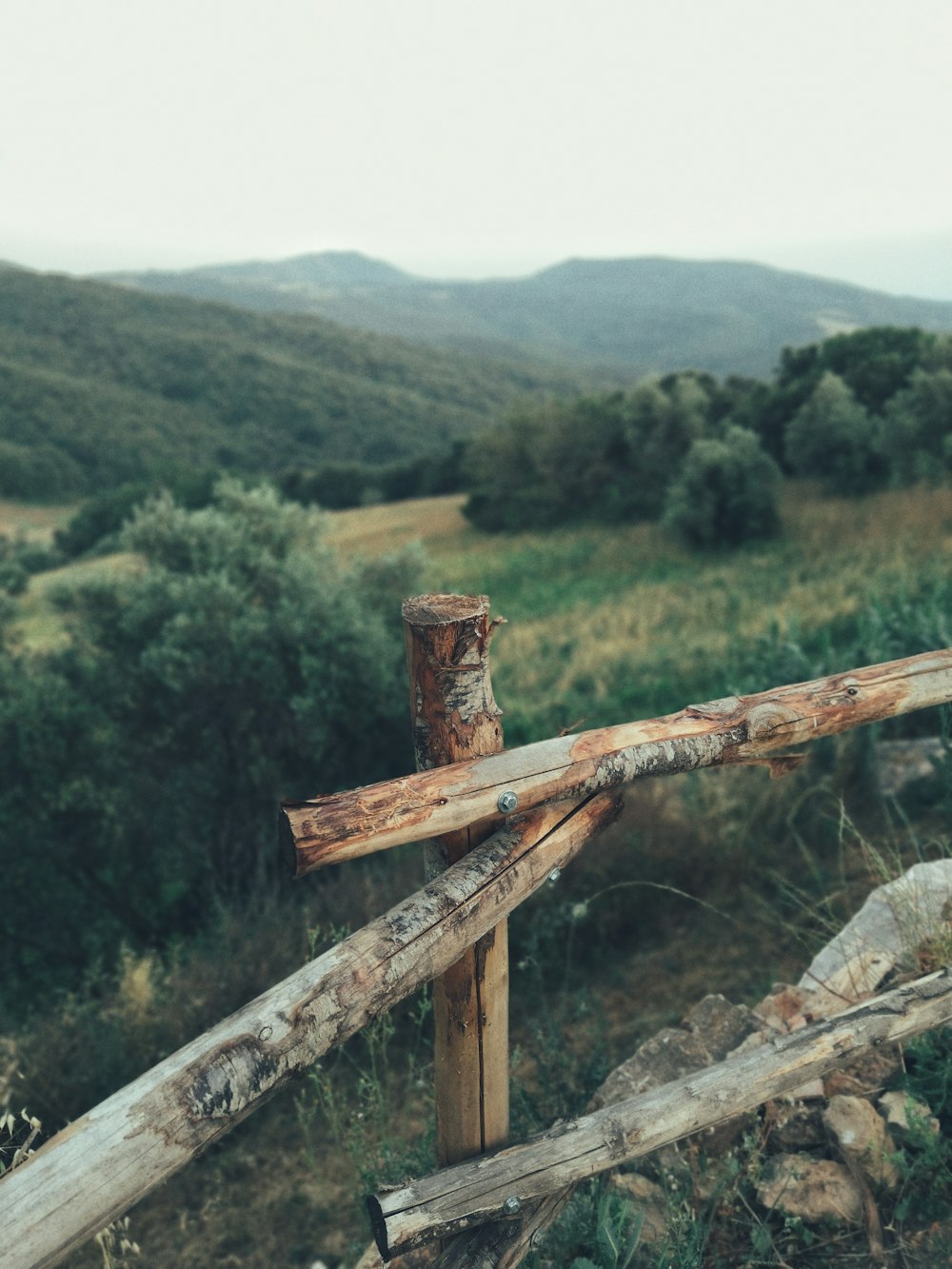 recinzione di legno marrone vicino ad alberi e montagne in lontananza
