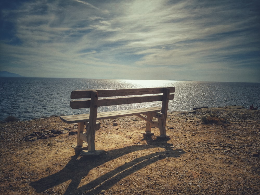 un banc en bois posé au sommet d’une plage de sable