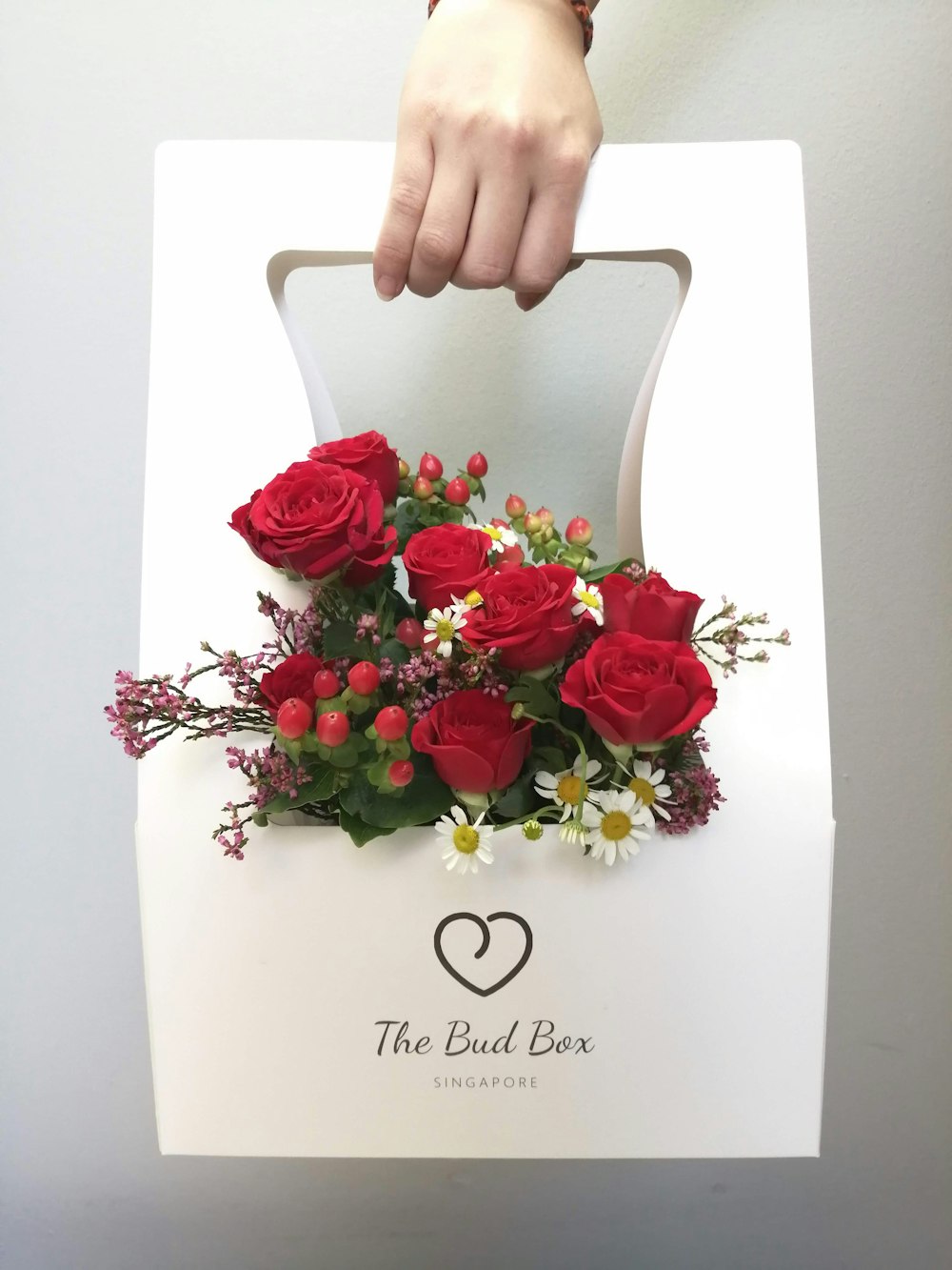 a person holding a white box with red roses in it