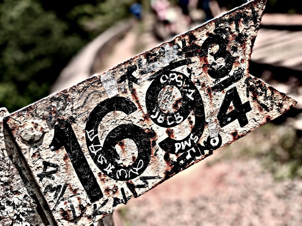 a close up of a rusty sign with graffiti on it