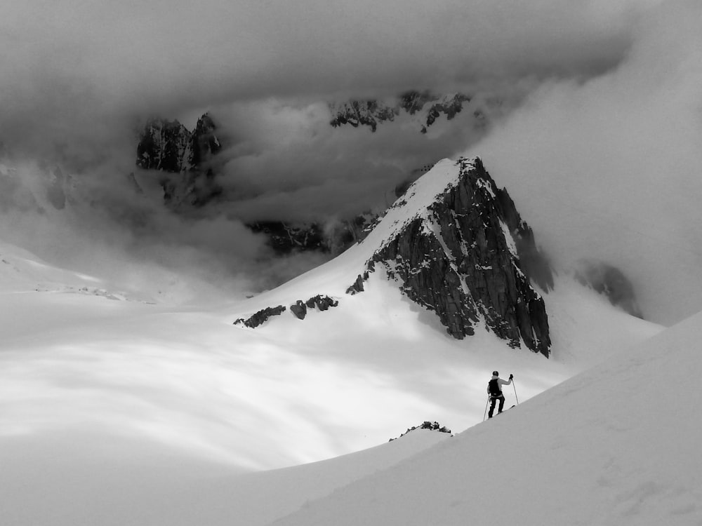 Photographie en niveaux de gris d’un homme grimpant sur une montagne