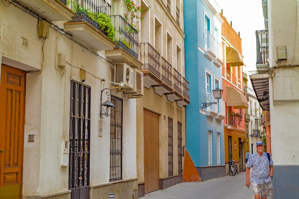 person walking beside white buildings during daytime