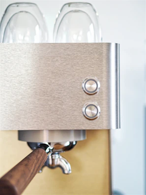 Close-up of a sleek Hambach espresso machine with polished metal and glowing buttons.