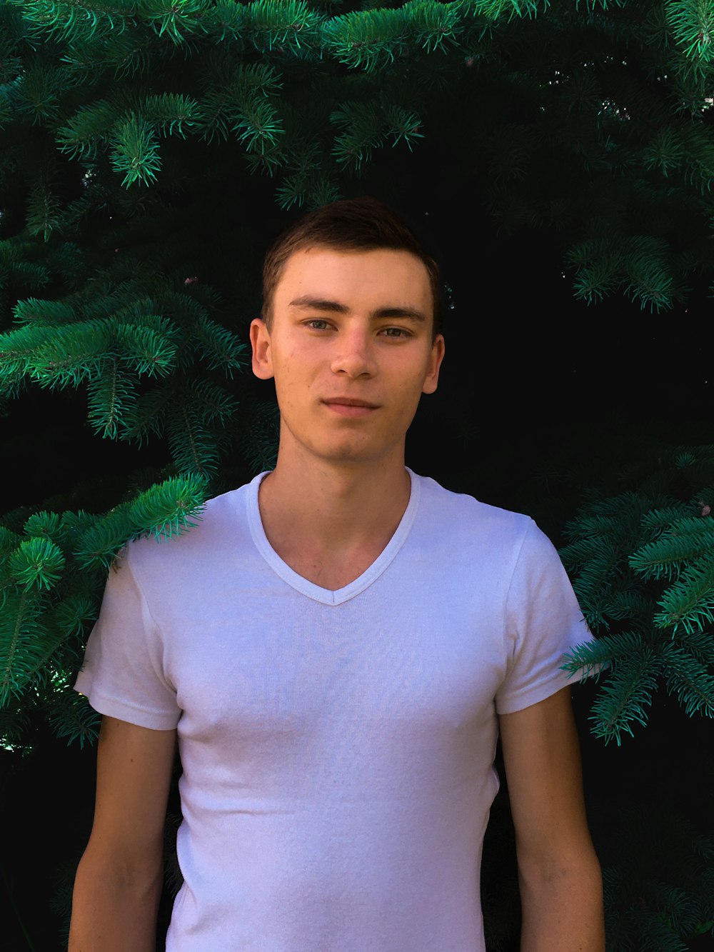 a young man standing in front of a tree