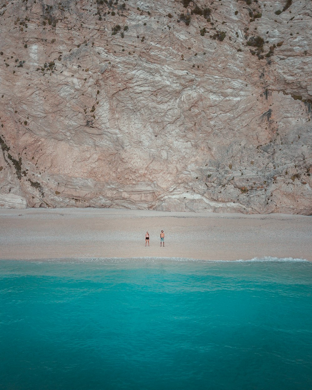 Dos personas paradas en la orilla cerca del cuerpo de agua