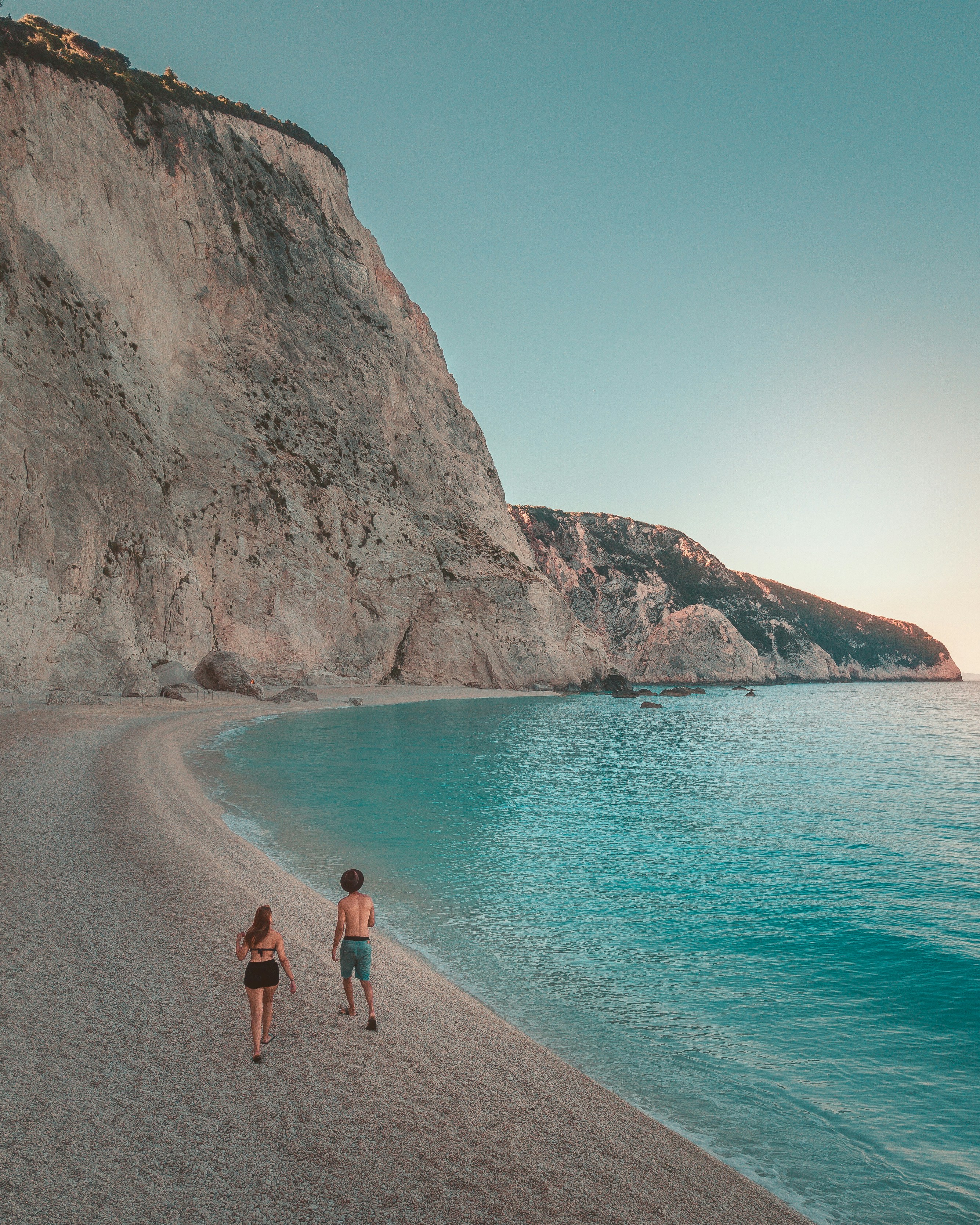 man and woman walking on beach during daytime