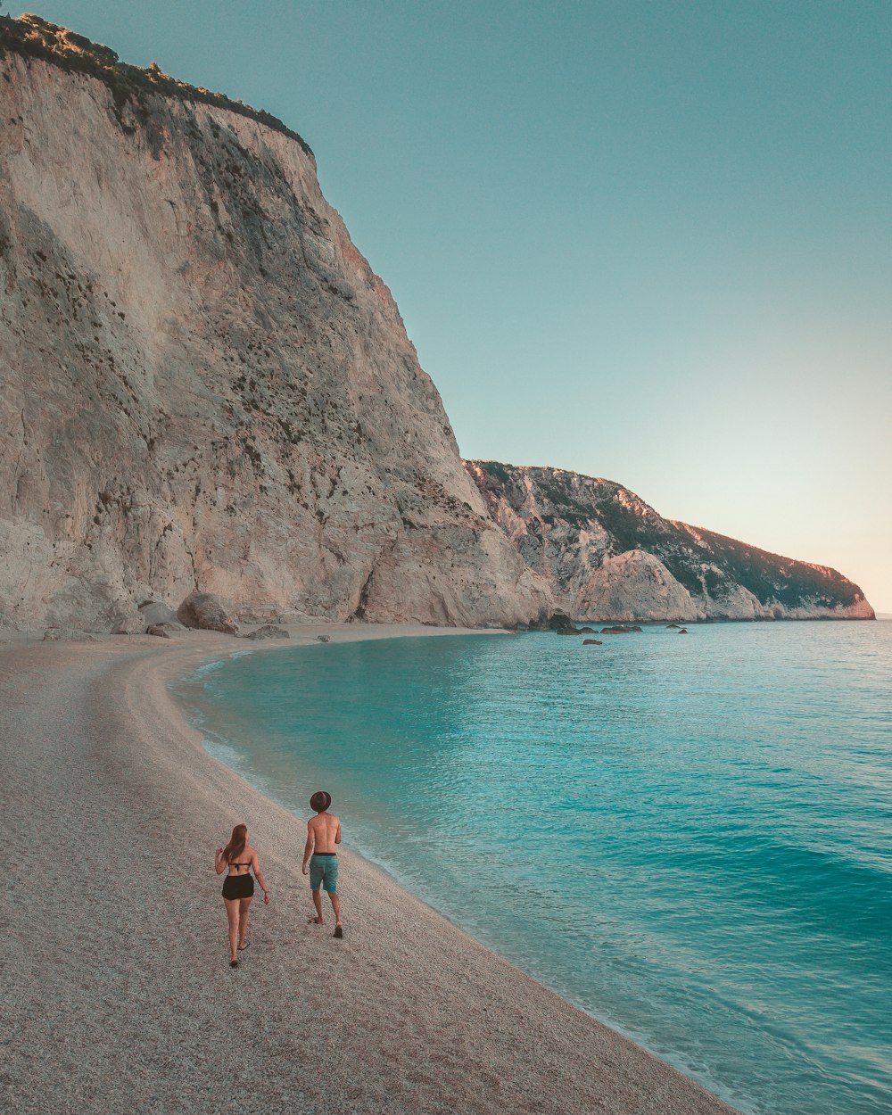 man and woman walking on beach during daytime