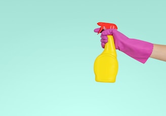 person holding yellow plastic spray bottle