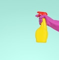 person holding yellow plastic spray bottle