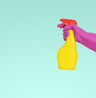 person holding yellow plastic spray bottle