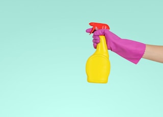 person holding yellow plastic spray bottle