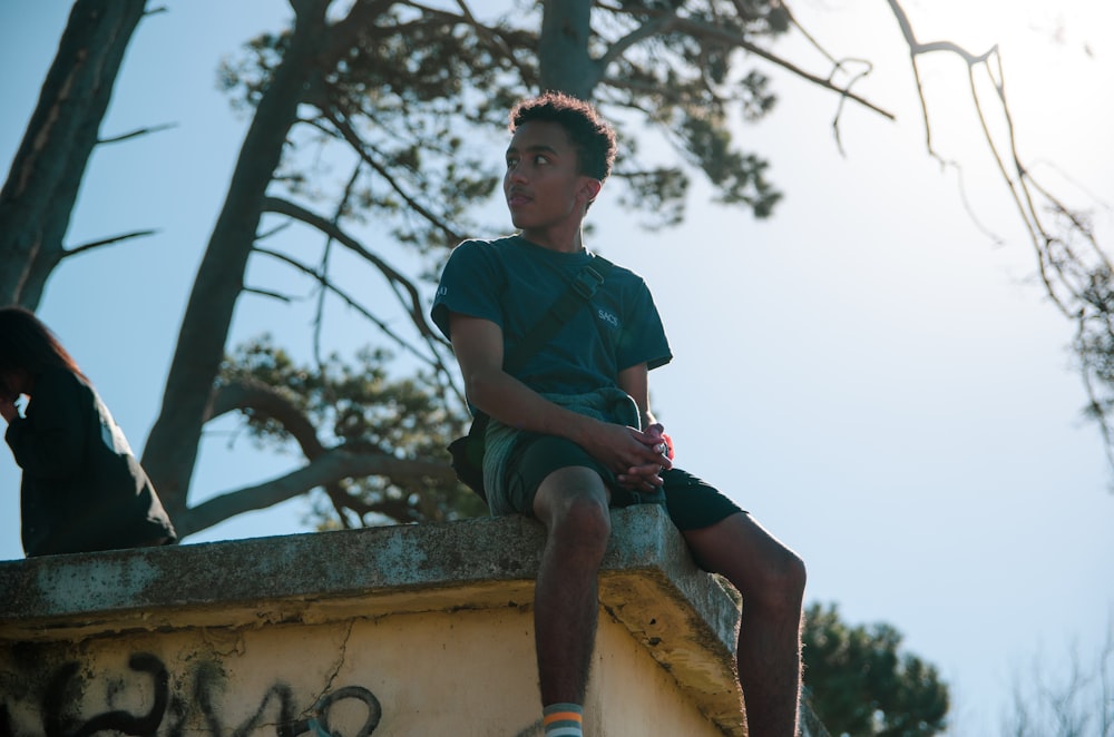 man wearing black shirt sitting on grey rooftop