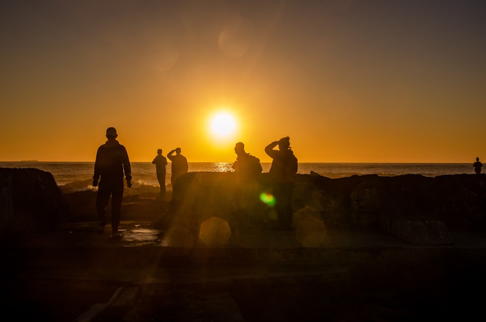 a group of people standing on top of a beach next to the ocean