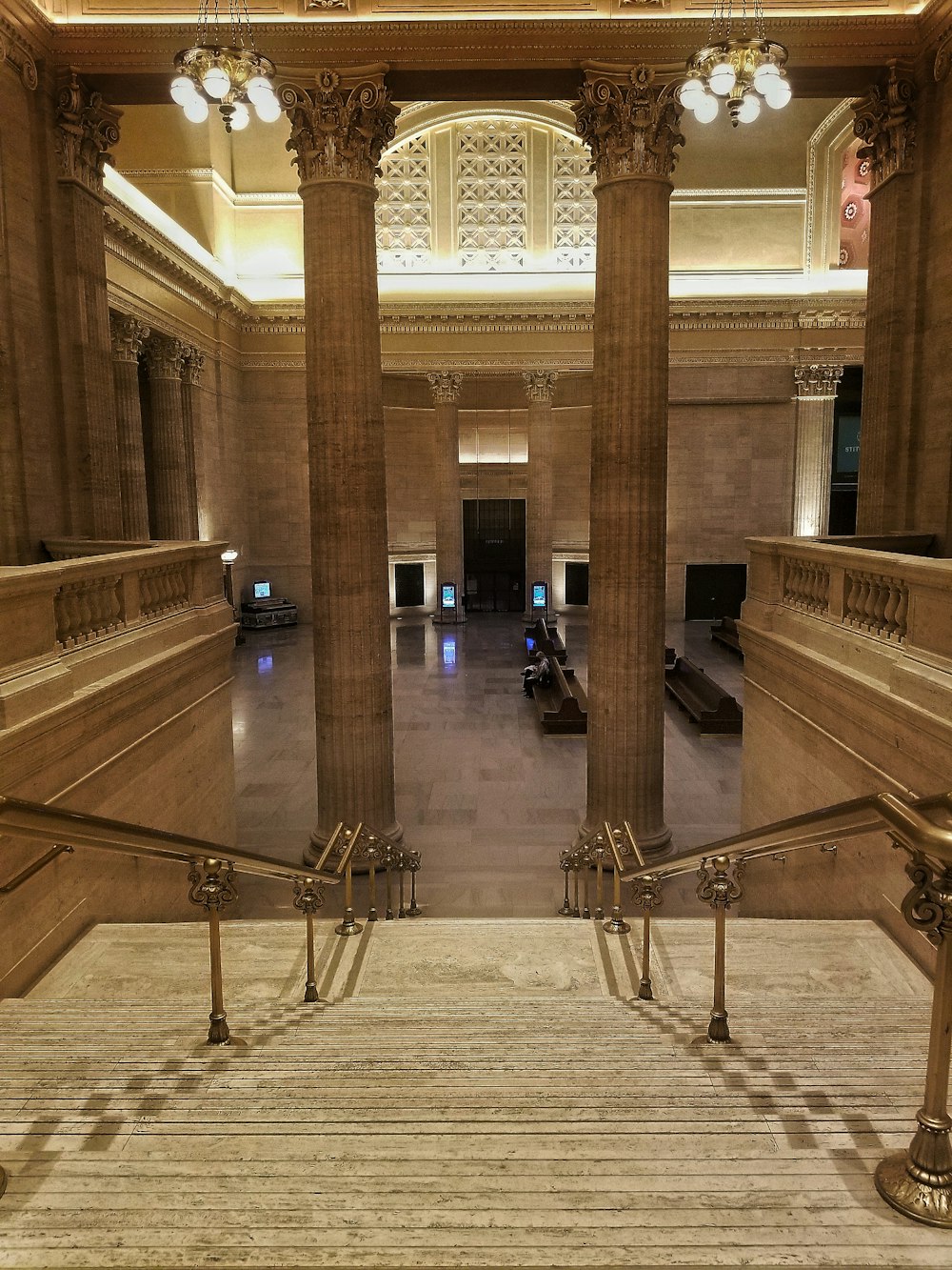 a staircase in a building with columns and a chandelier