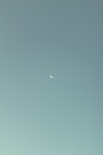 an airplane flying in the sky with a half moon