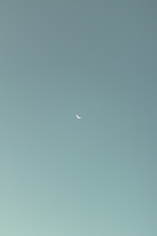 an airplane flying in the sky with a half moon