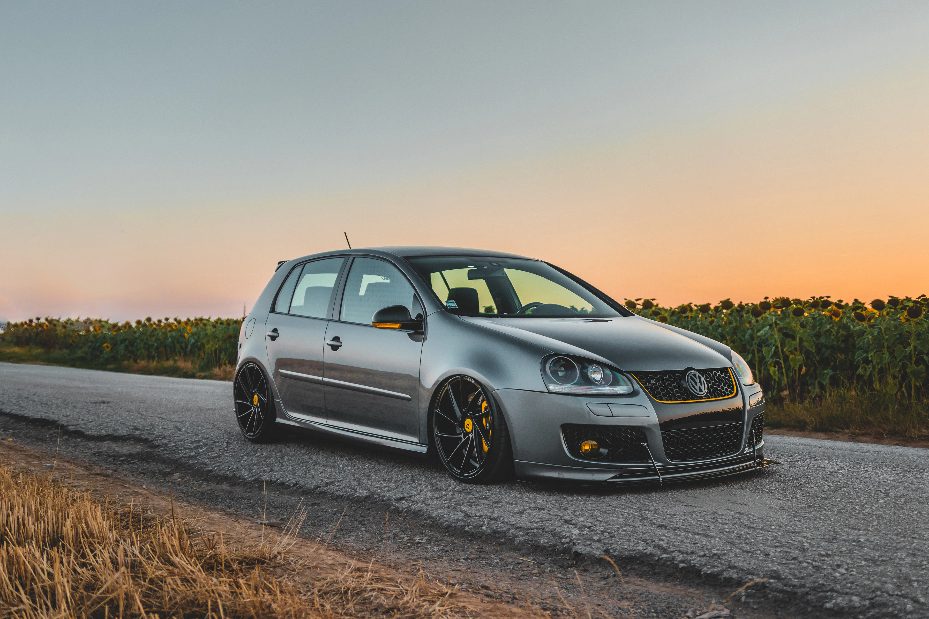 Grey Volkswagen Golf V on a country road at sunset