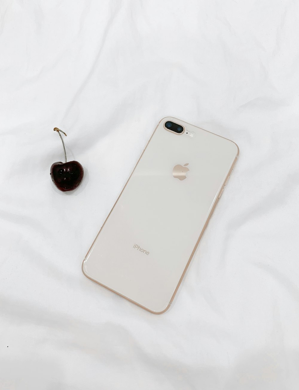 white iPhone 8 and red cherry fruit