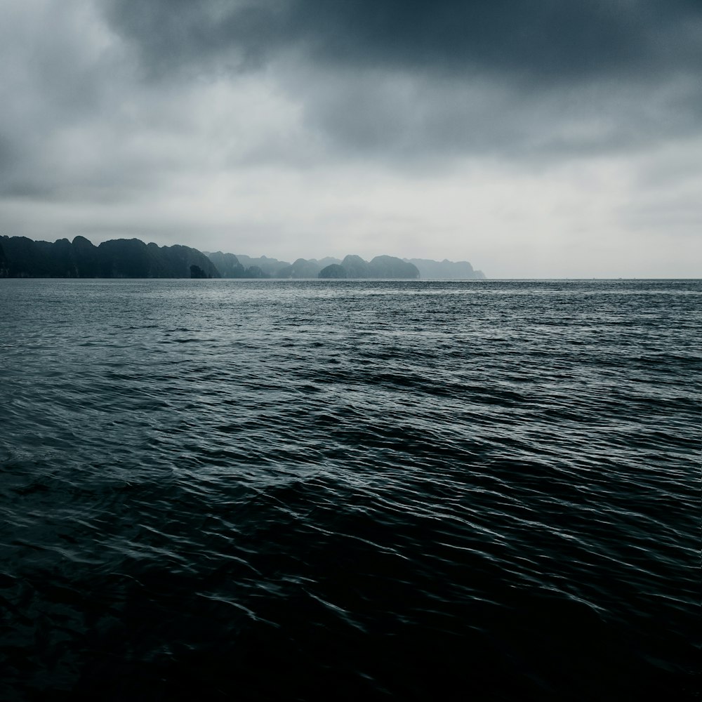 body of water under gray clouds at daytime