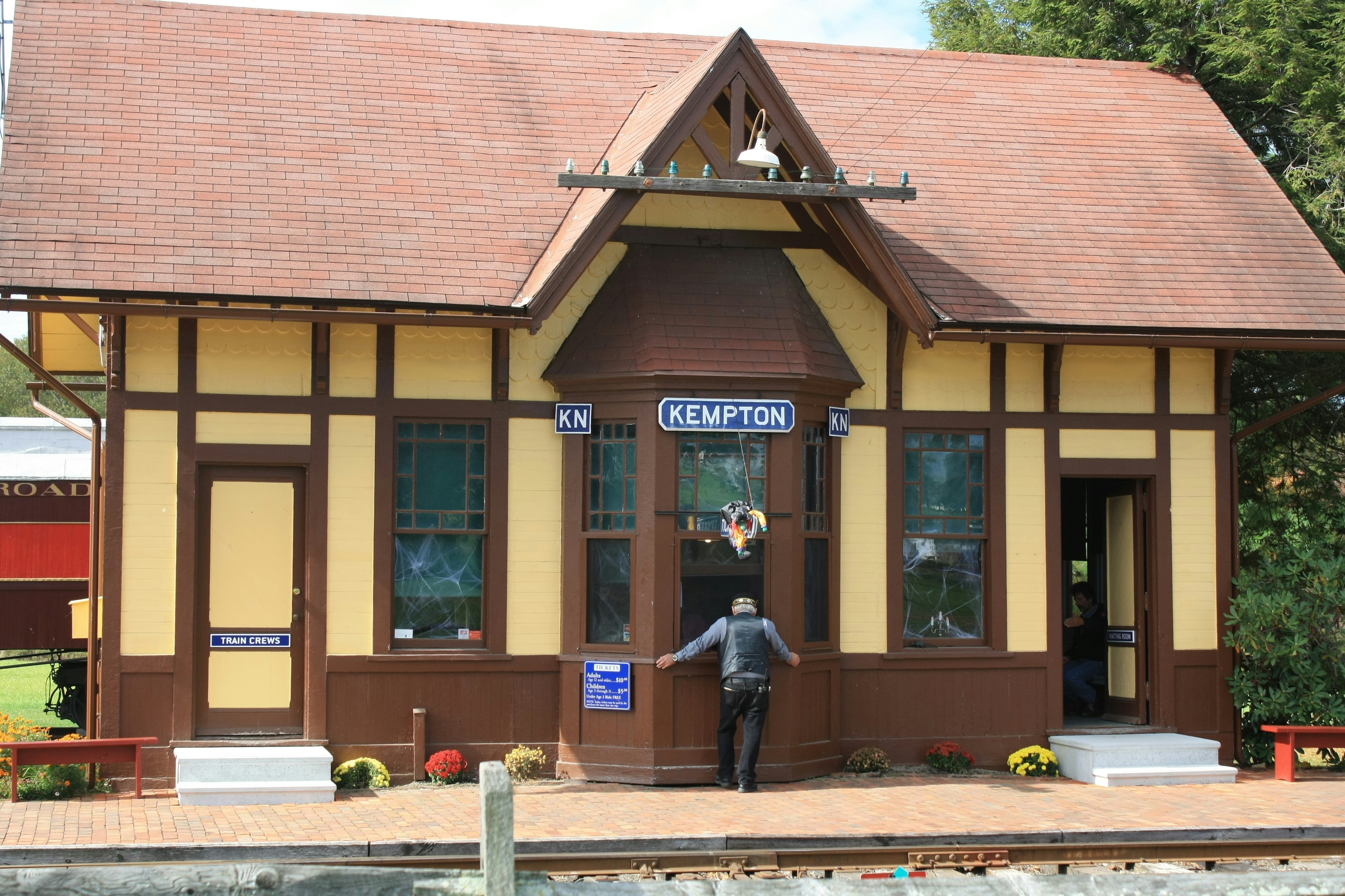 man standing beside brown Kempton building