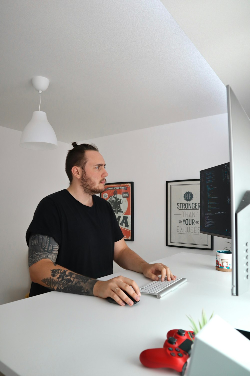 standing man wearing black crew-neck t-shirt holding mouse and keyboard