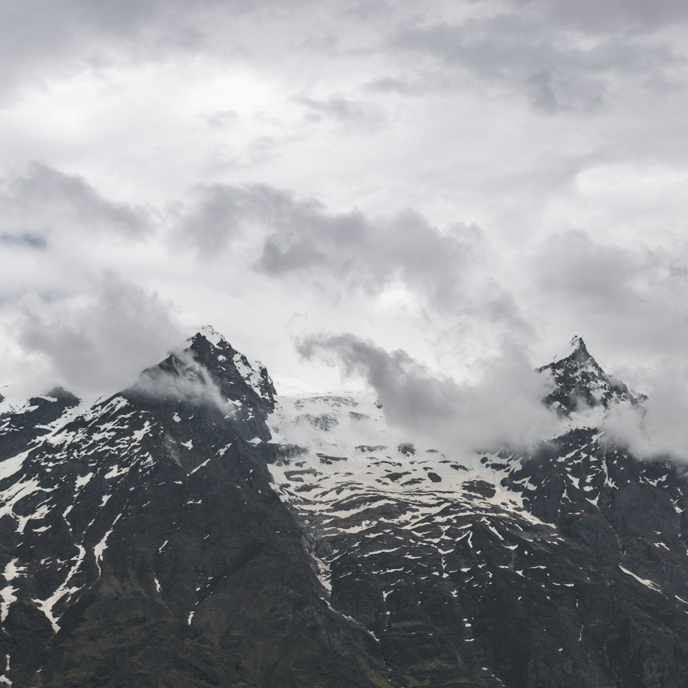 a group of mountains covered in snow under a cloudy sky