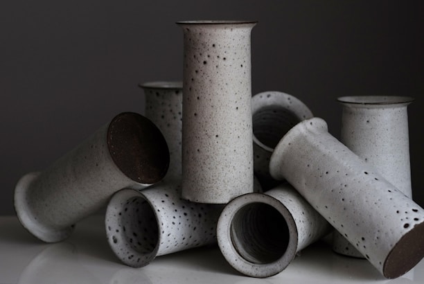 A collection of handmade ceramic vases in soft pastel colors arranged on a wooden table.