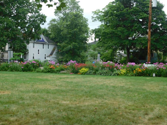 A serene backyard with neatly trimmed lawn and blooming flower beds.