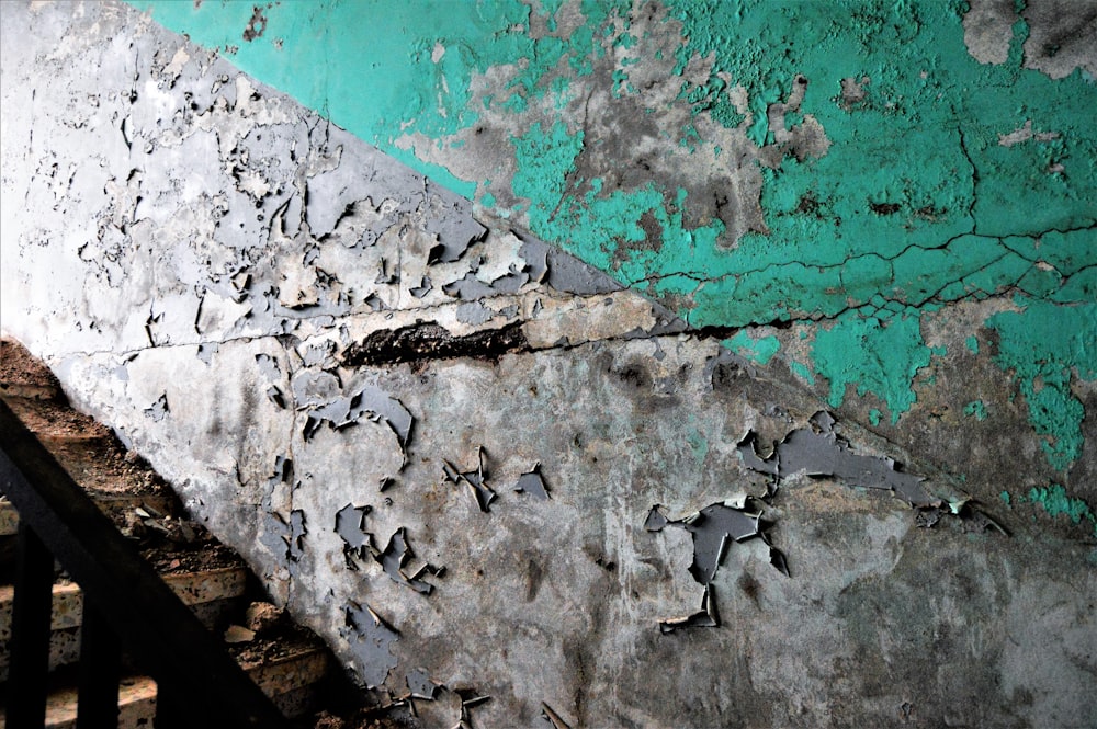 a green and gray wall with peeling paint on it