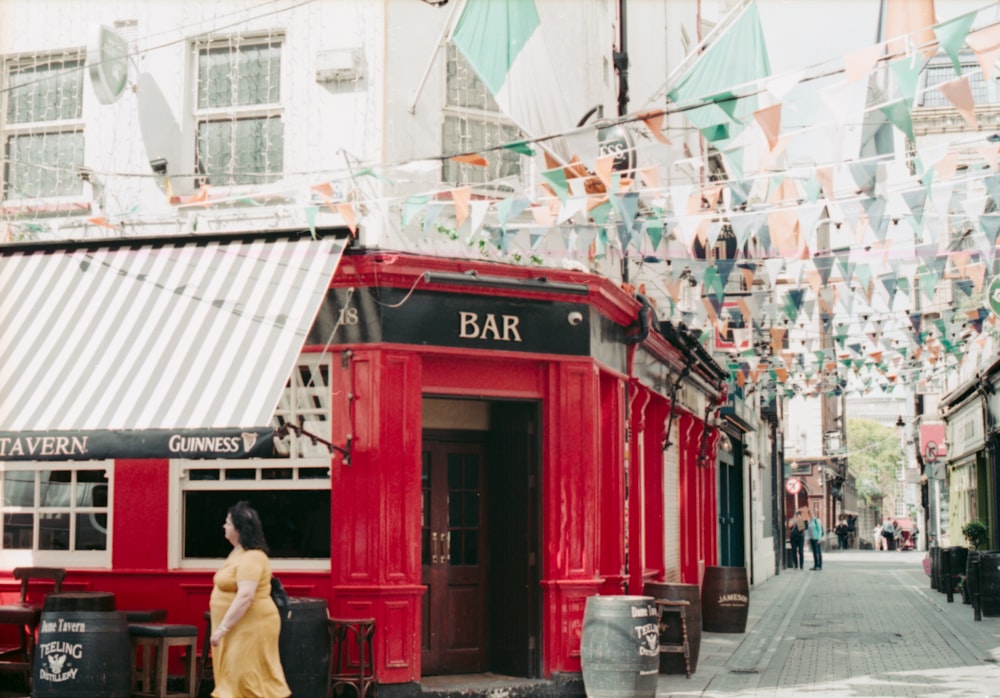 woman wearing yellow dress walking besides Bar