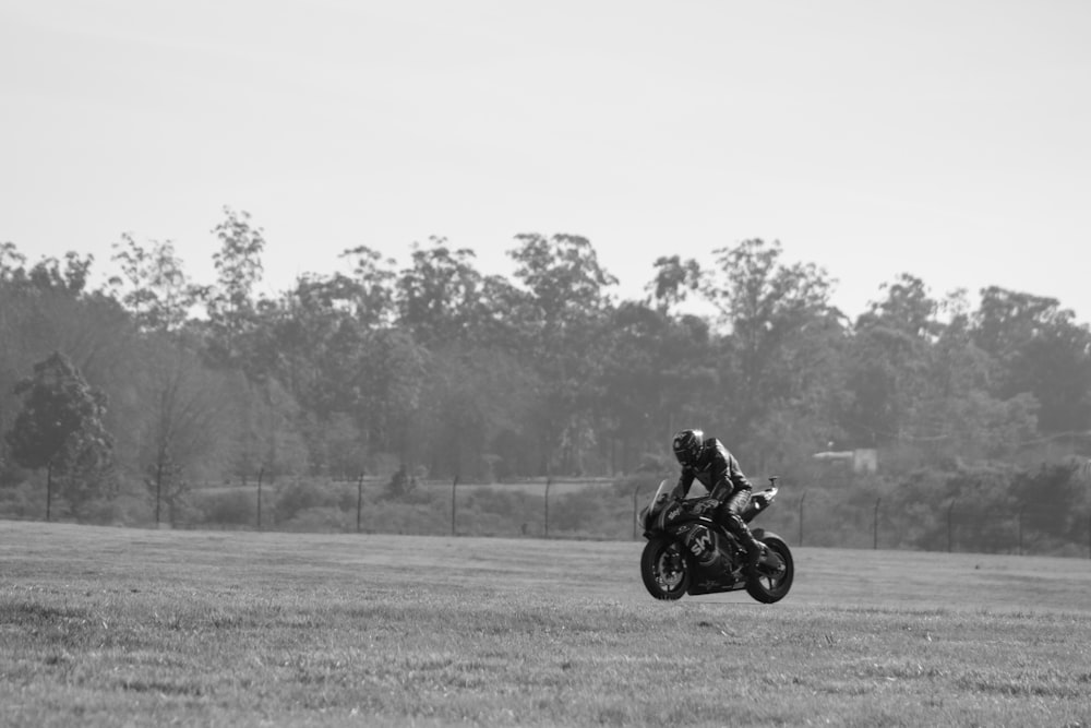 grayscale photo of man riding sports bike