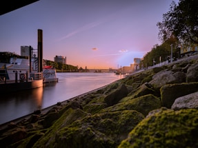 A serene riverside scene at sunset with a small boat docked near lush Amazonian forest.
