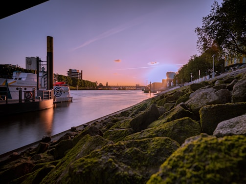 A serene riverside scene at sunset with a small boat docked near lush Amazonian forest.