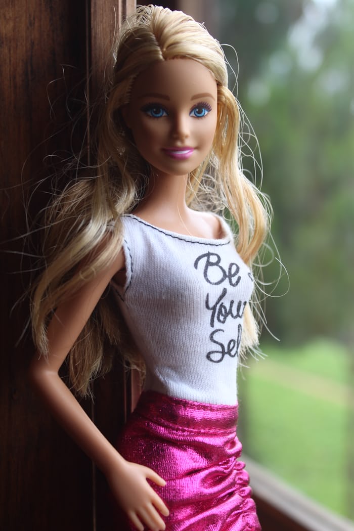 Blonde Barbie wearing the color pink (skirt) and smiling.
