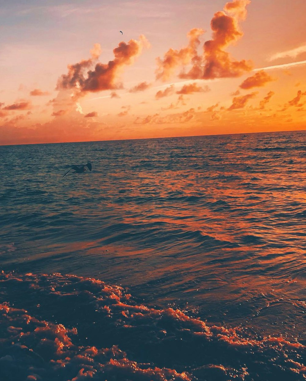 a person riding a surfboard in the ocean at sunset