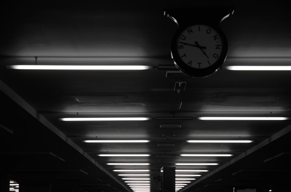 a black and white photo of a clock hanging from the ceiling