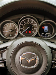 Close-up of a Mazda steering wheel with dashboard lit up during a test drive.