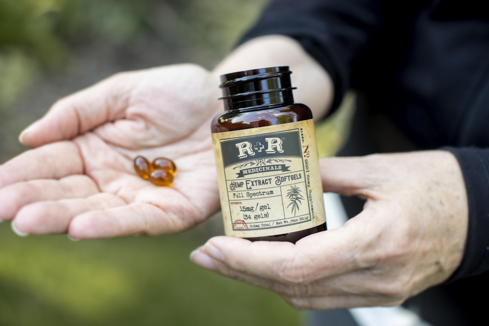 person holding R+R bottle and 3 gel capsules