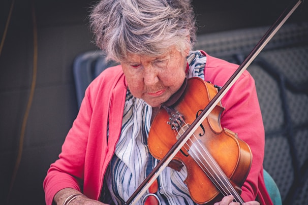 Therapist assisting an elderly person with a musical instrument.