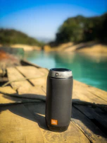 A close-up of a black and green portable Bluetooth speaker on a dark background.