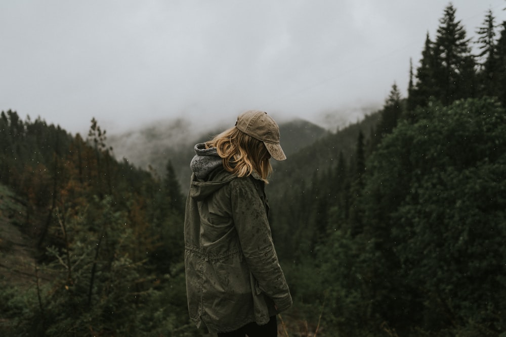 Mujer con abrigo gris de pie en el bosque