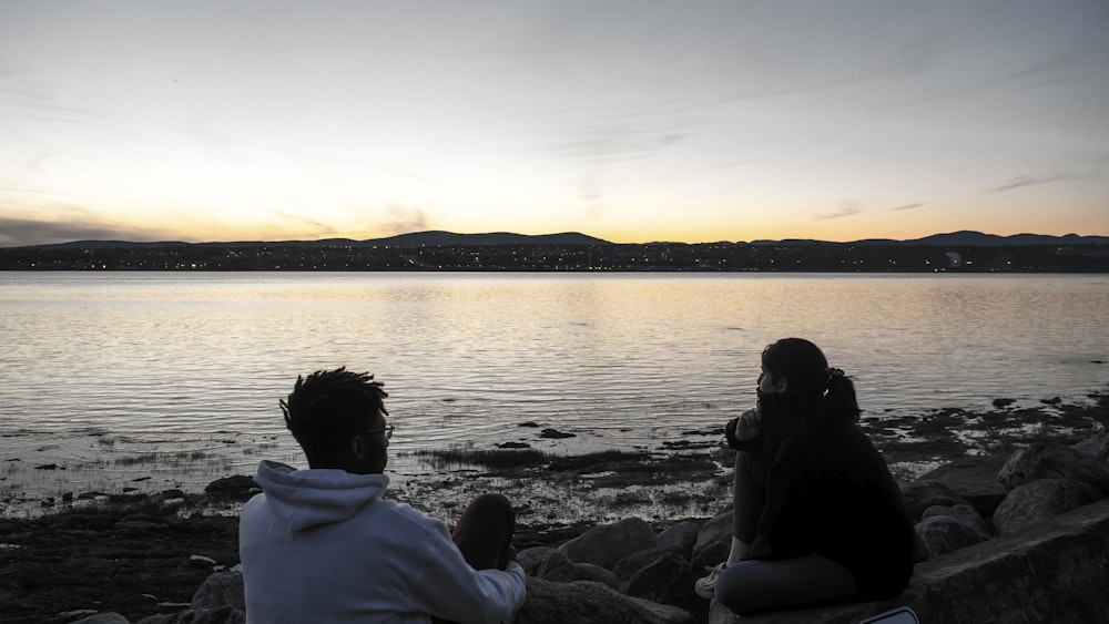 man sitting beside seashore